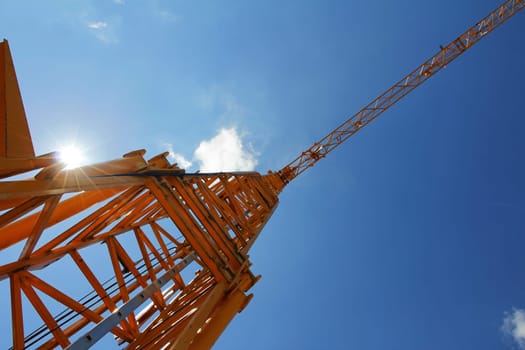 A yellow construction crane against the blue sky