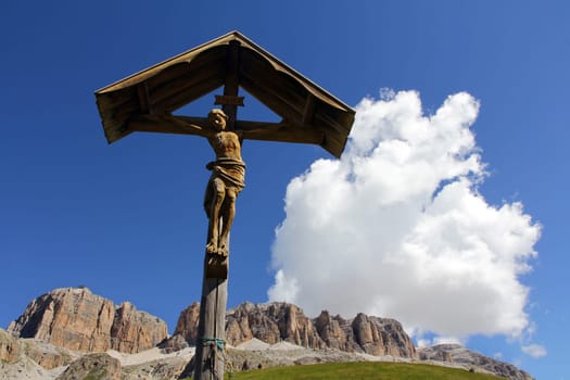 A Christian cross made of wood in the mountains. Wooden cross with Jesus in the Dolomites in Italy