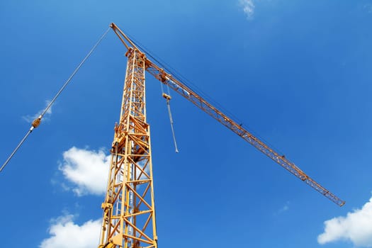 A yellow construction crane against the blue sky