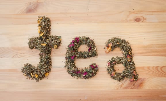Tea lettering made of loose tea on rustic background made of wood