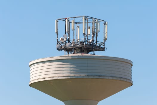 Water tank tower surmounted with a telephone repeater antennas against il cielo blu.Copy space