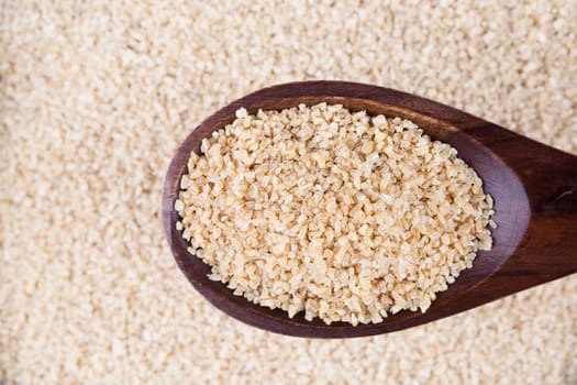 Wooden spoon full of bulgur wheat.