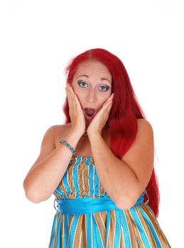 A pretty woman in her thirties with long red hair holding her face is.shocked what she sees, isolated for white background..