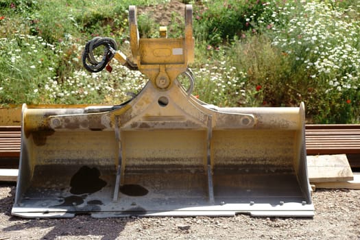 The close-up of an excavator shovel next to tools and materials.