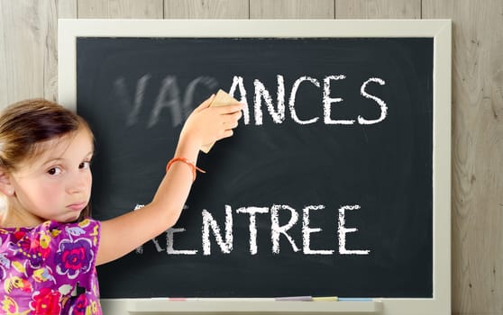 a young girl clears "vacances"" on blackboard"