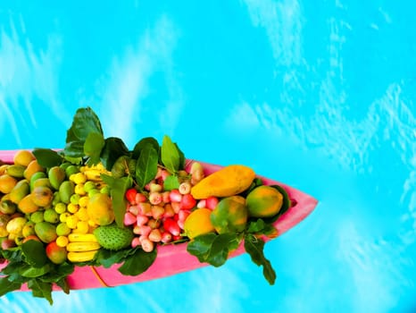The exotic tropical fruits on the boat canoe against blue water