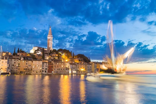 Coastal town of Rovinj, Istria, Croatia in sunset. Motion blur of sailing fishing boat can be seen on right side.