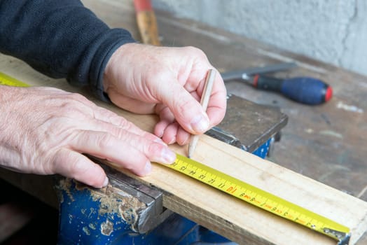 carpenter measuring a wooden board with pencil