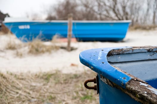 two blue rowing boats in the dunes on the Baltic Sea beach on the island of Usedom Front of a worn boat sharp in the foreground,second boat lies across in the blurred background between dry dune grass