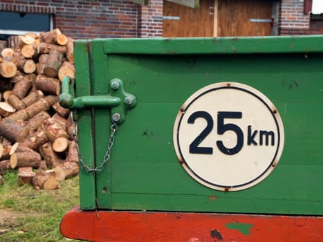Close-up of the tailgate with locking of a green trailer with a round white sign and the inscription "25km"" as the maximum speed"