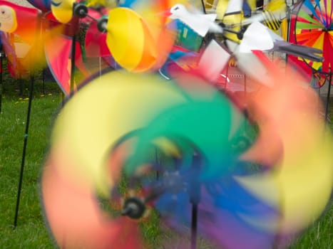 colorful rotating children's wind turbines recorded on a meadow with long exposure time