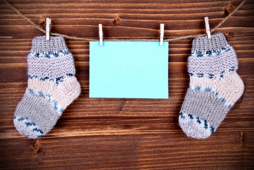 Blue Tag Or Label With Two Baby Socks On A Line With Copy Space For Your Free Text Here On Wooden Background, Vintage, Retro And Old Fashion Style With Frame