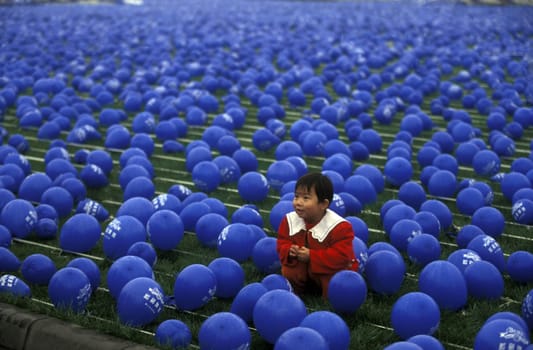 a chila in blue ballons on a economy fair in the city Square of Chengdu in the provinz Sichuan in centrall China.