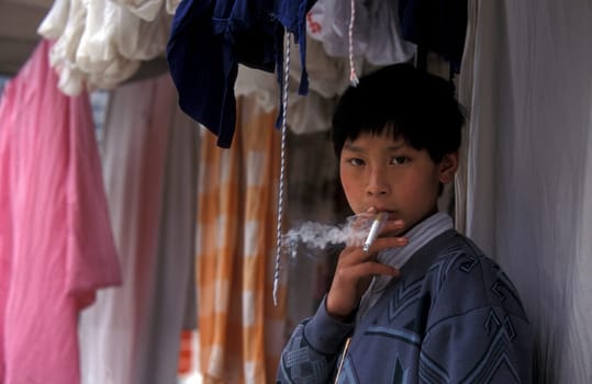 a boy is smoking cigarets at the yangzee river in the three gorges valley up of the three gorges dam project in the province of hubei in china.
