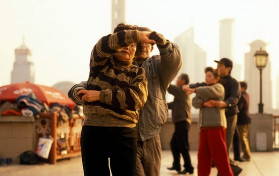 people dancing in the morning on the Bund in front of the skyline of Pudong in the City Shanghai in China.