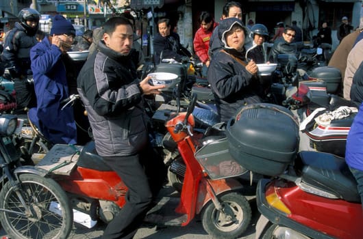 people eat a noodle soupe in the trafic line in the City of Shanghai in china in east asia.