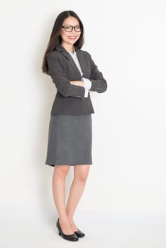 Full body Asian business woman standing on plain background.