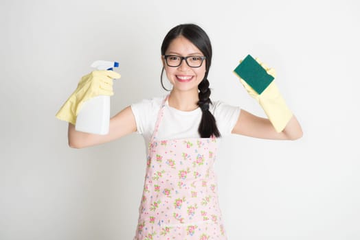 Asian Chinese young woman housewife, spraying detergent and wiping over dirty glass.