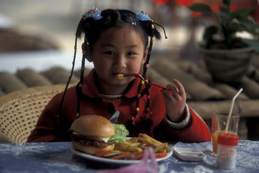 a girl with a hanburger in a restaurant in the town of Yangshou near the city of Guilin in the Province of Guangxi in china in east asia.