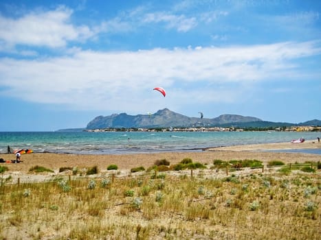 Pollenca, Majorca, Spain - June 28, 2008: Kite surfers at bay of Pollenca - somewhere between Pollenca and Alcudia, view towards peninsula Victoria, north of Majorca - natural beach in front
