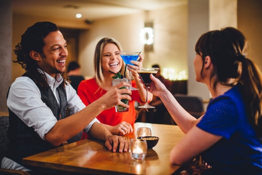 Group of friends toasting cocktails in a restaurant.