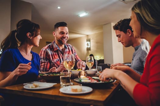 Group of friends enjoying an evening meal with wine at a restaurant.