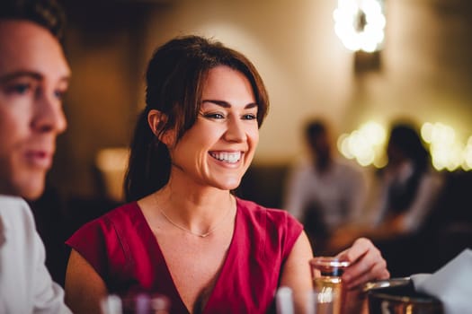 Close up of a mature woman at a restaurant. She is enjoying a glass of champagne with her friends.