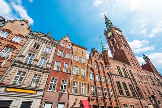 Old and colorful houses in street of Gdansk, Poland, Europe. Beautiful sunny day, blue cloudy sky. Gothic-Renaissance town hall tower.