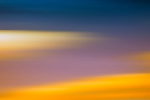 A blurred sky with different colored and colorful clouds.