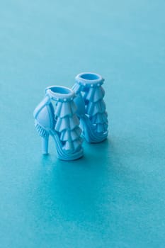 Blue high-heeled doll shoes on a blue background