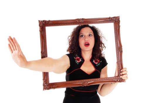 A angry woman looking trough a picture frame stretching one hand.out say NO, isolated for white background..