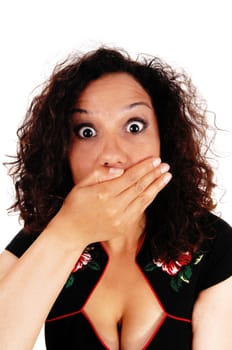 A beautiful young woman with curly brunette hair is frightened, holding.her hand over her mouth and her eye's wide open..