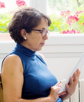 a portrait of a mature woman with a tablet near a window