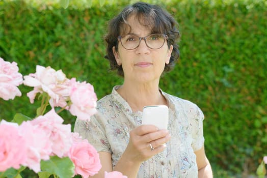 portrait of a mature woman with a phone in her garden