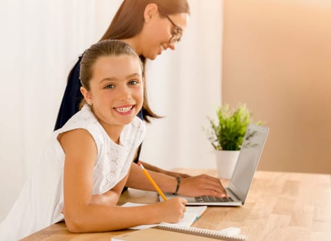 Mother helping her little daughter how to use a computer