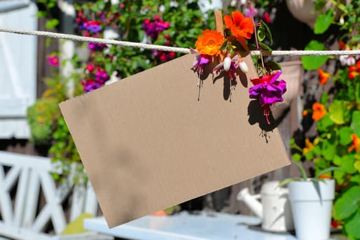 Sheet of paper on clothesline in front of colorful flowers