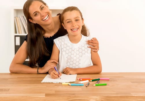 Mother helping her little daughter making drawings