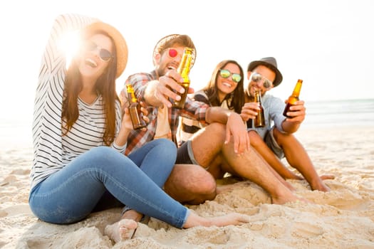 Friends having fun together at the beach and drinking a cold beer