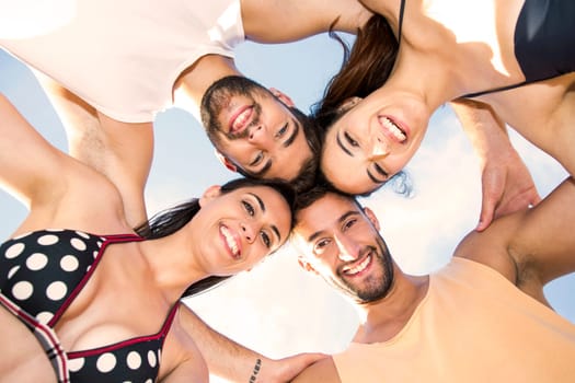 Multicultural group of friends embraced together at the beach