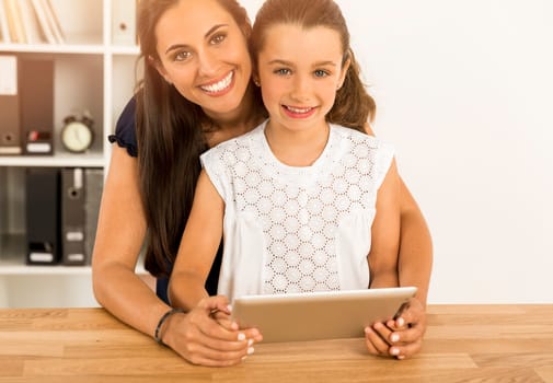 Mother helping her little daughter how to use a computer