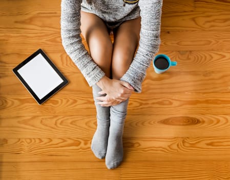 Woman sitting on the floor drinking a coffee and texting