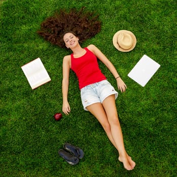 Happy young woman sitting on a blanket with arms stretched
