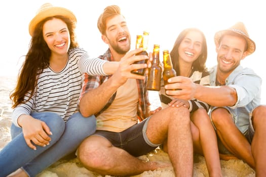 Friends having fun together at the beach and drinking a cold beer