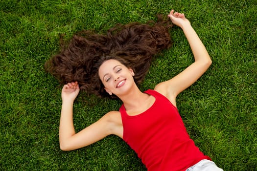 Outdoor portrait of a beautiful young woman lying on the grass