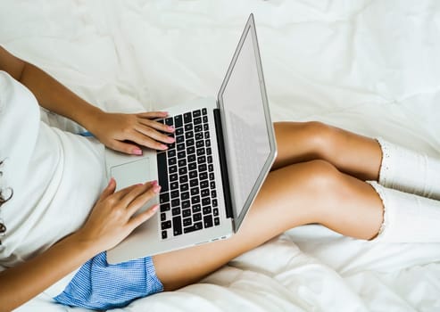 Beautiful woman working with a laptop on the bed