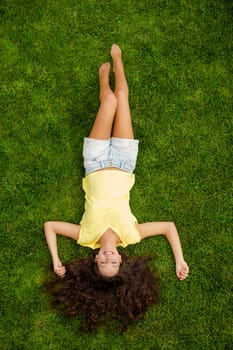 Portrait of a beautiful and happy young woman lying on the grass