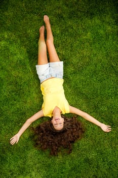 Portrait of a beautiful and happy young woman lying on the grass
