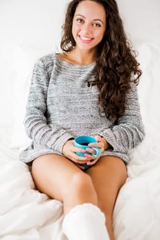 Beautiful woman on bed drinking a coffee