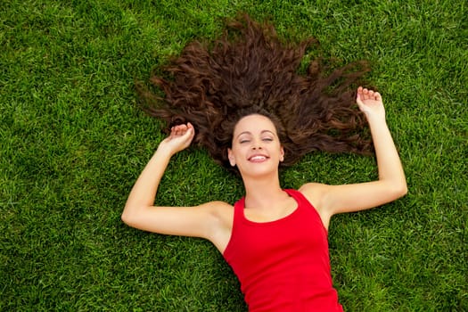 Outdoor portrait of a beautiful young woman lying on the grass