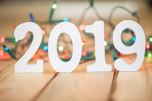 Numbers made of wood 2019 in front of colorful string of lights,selective focus
